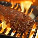 Saucey barcecue ribs on a flaming grill