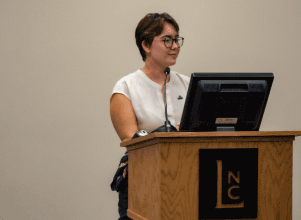 Rebecca Hart speaking at podium